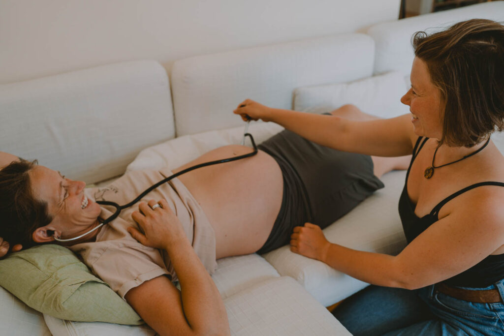 Hebamme hört Herztöne ab, dokumentiert in einer authentischen Businessreportage